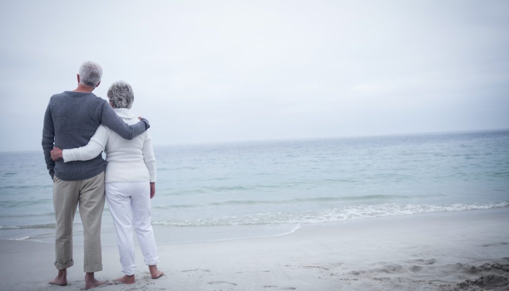 Rear view of senior couple embracing on beach