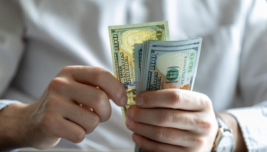 man counting hundred dollar bills. dollar investment and cost of living