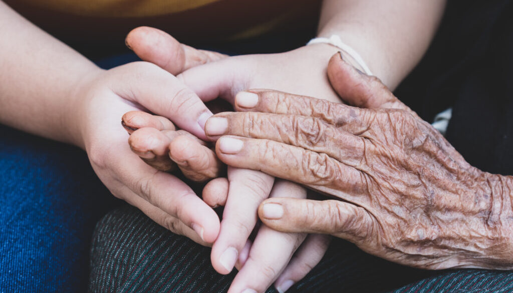 Young grandchildren's holding older grandmother hands feel with support together, wrinkled skin with feeling take care. World Kindness Day, Adult day center Relationship of Family mother day concept