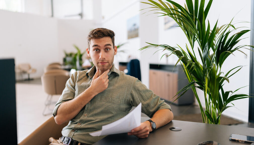 Portrait of focused male client reading contract for real estate property purchase. Thoughtful man reading terms of conditions of document, making decision