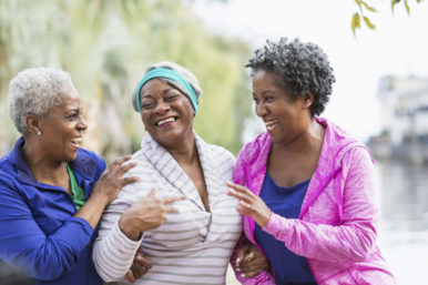 Three senior black women laughing together outdoors