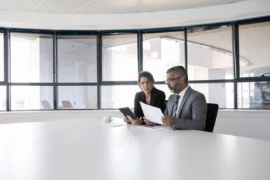 company-executives-analyzing-discussing-reports-two-business-colleagues-sitting-together-looking-document-holding-tablet-talking-wide-shot-communication-concept SMALL recolor