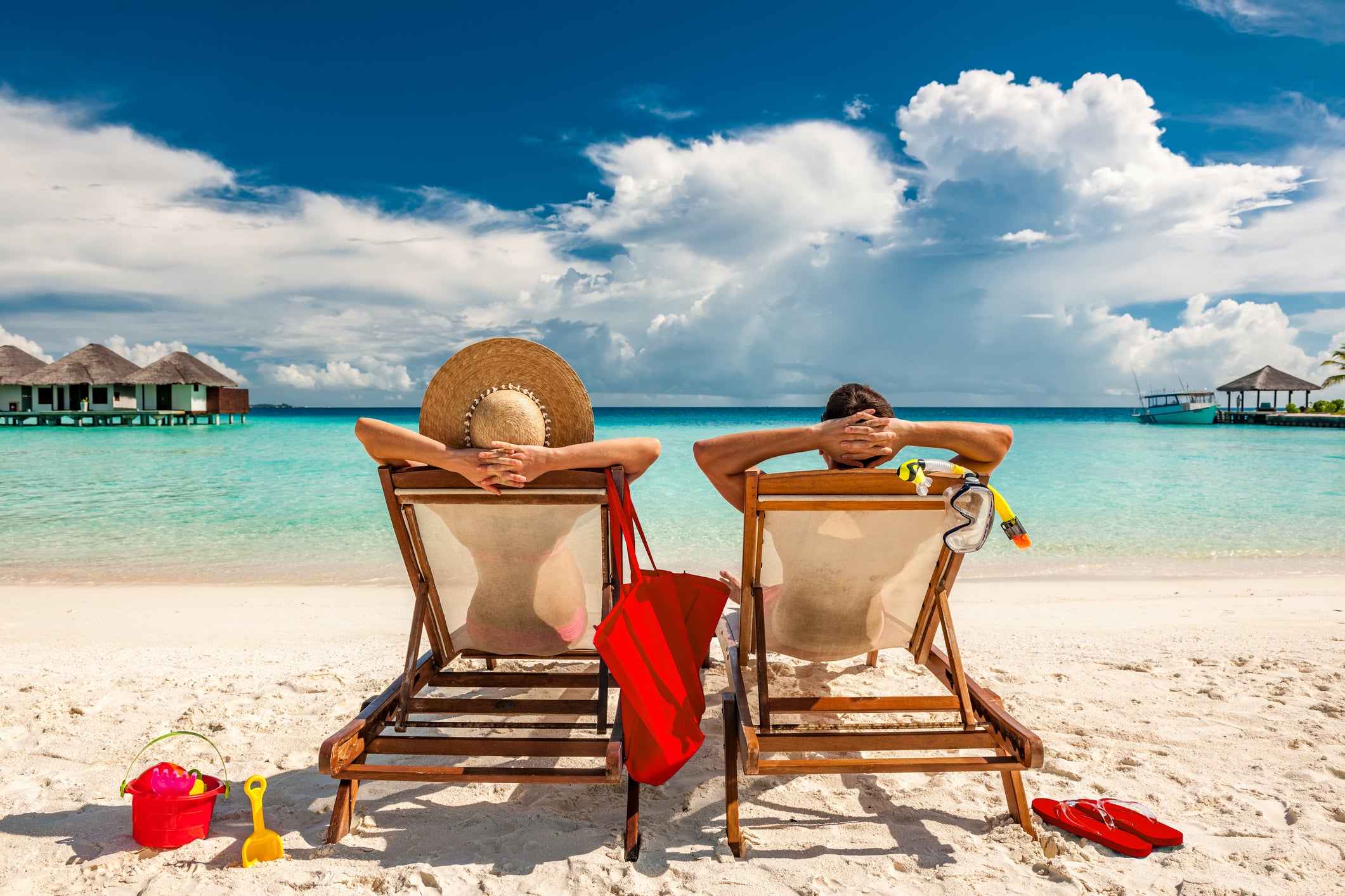 man-and-woman-relaxing-in-lounge-chairs-on-a-beach-in-the-maldives-mature-couple-vacation-early-retirement